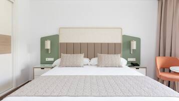 A hotel room with a large bed, two bedside tables, a chair, and a green accent wall.