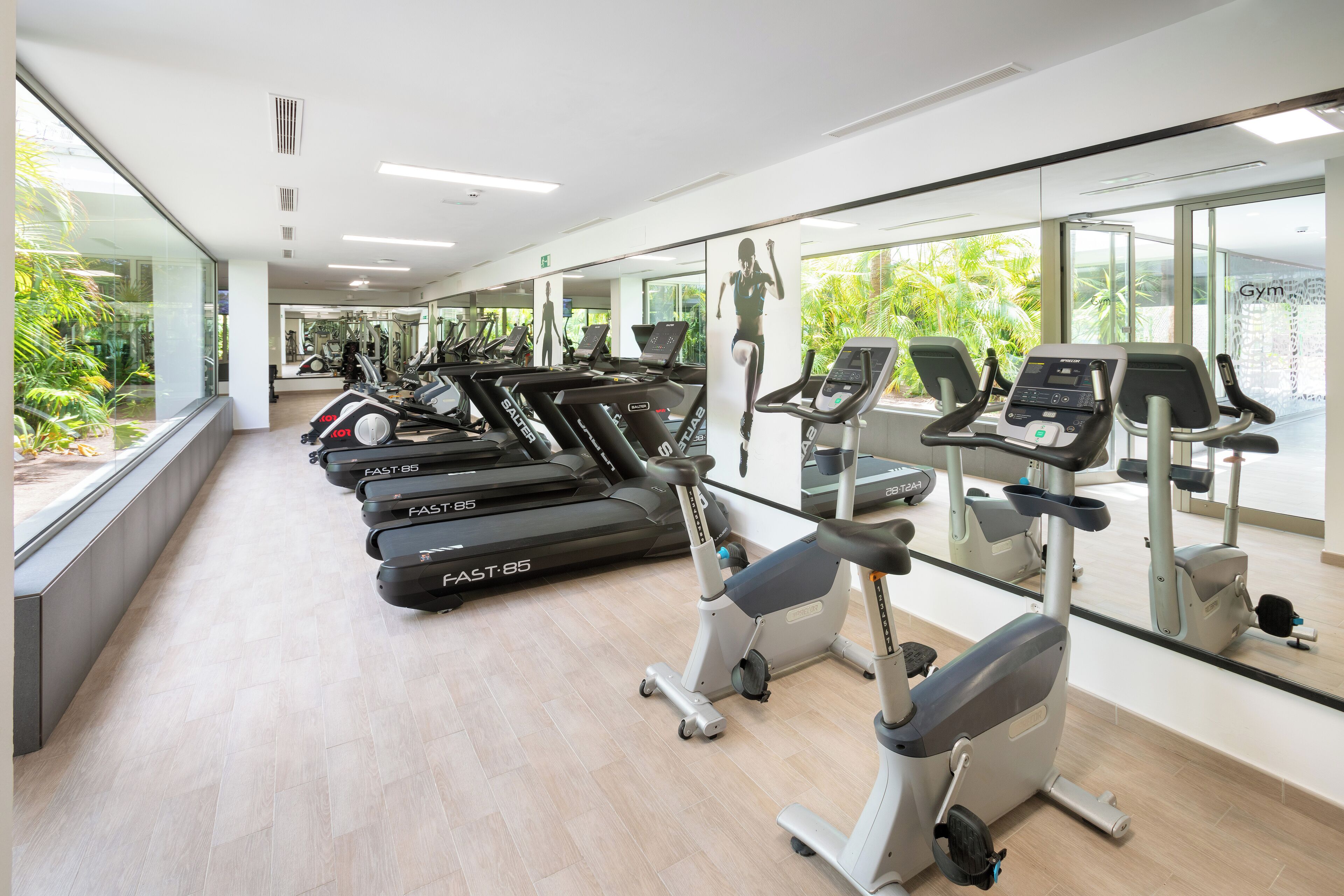 Un gimnasio con cintas de correr, bicicletas estáticas y elípticas.