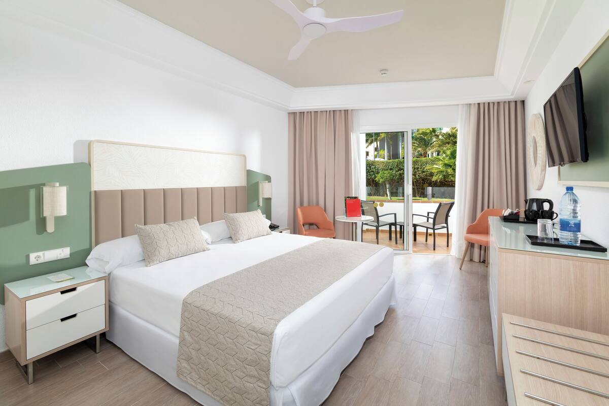 A hotel room with a bed, nightstand, desk, and a TV.