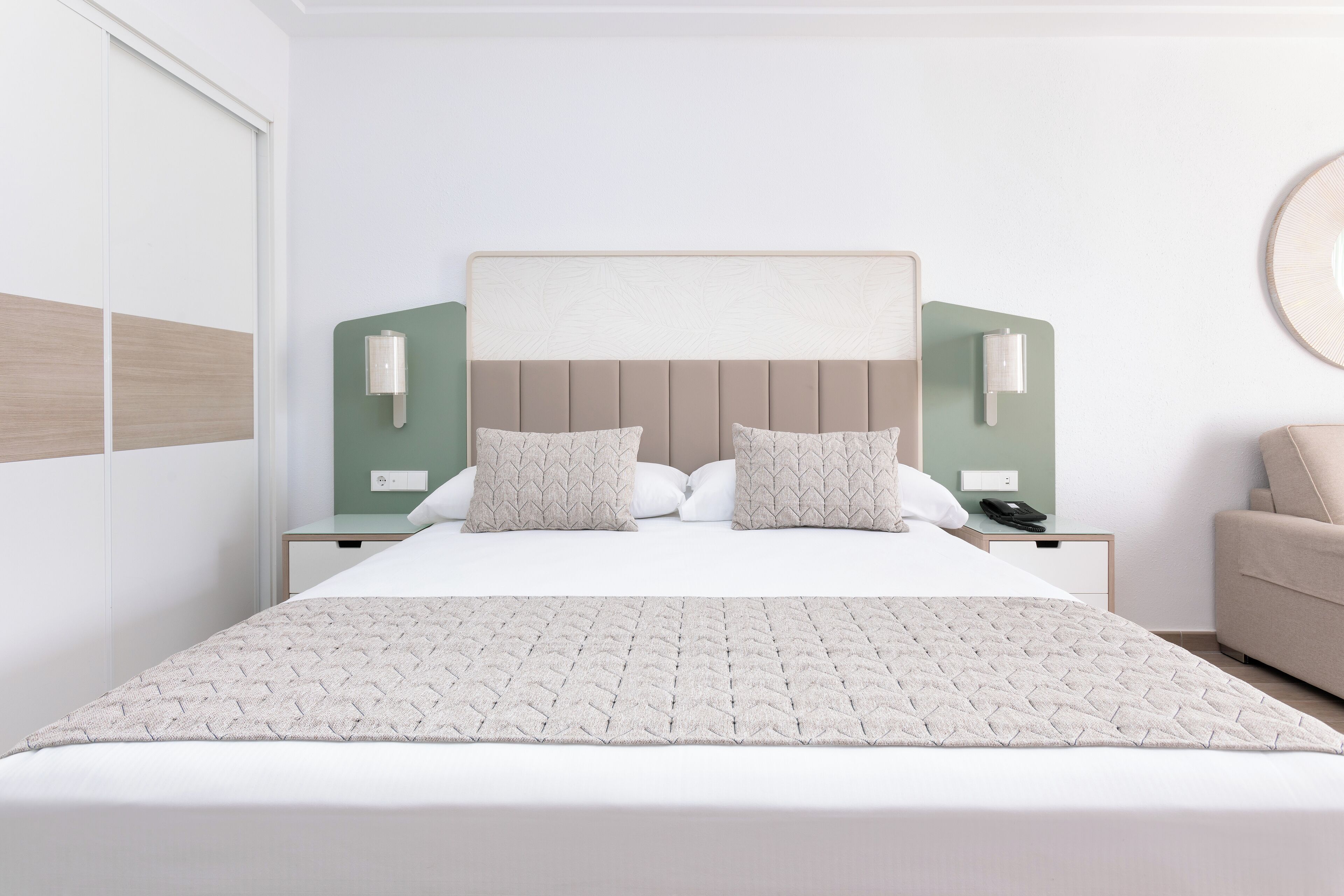 Een netjes ingerichte slaapkamer met een groot bed, twee nachtkastjes, een wandlamp en een nachtkastje.