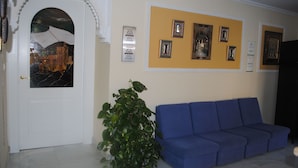 A room with a white door, a blue sofa, and a wall with framed pictures and plaques.