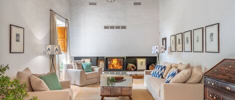 A living room with a fireplace, two sofas, a coffee table, and a wooden cabinet.