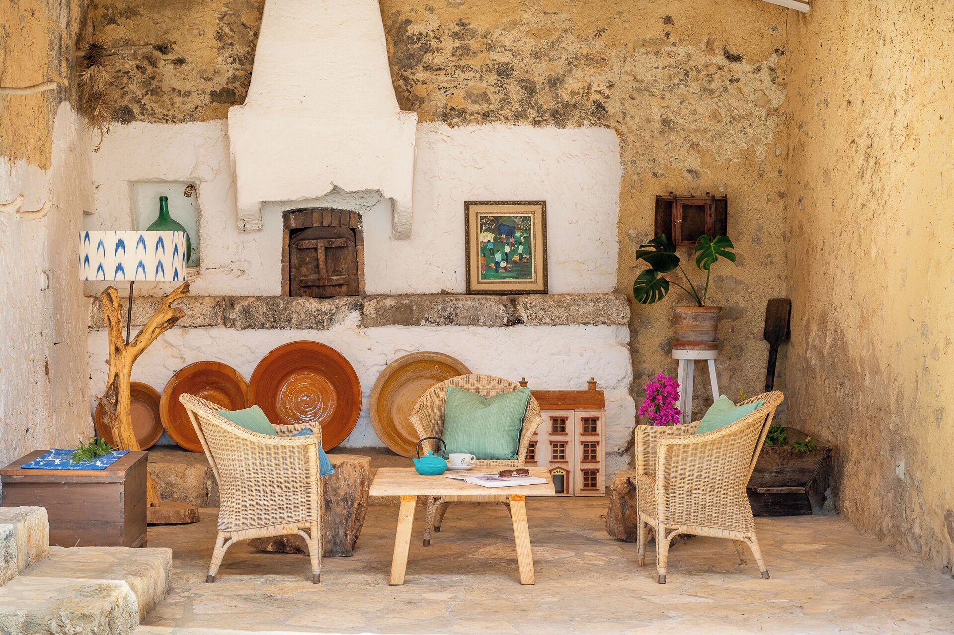An outdoor seating area with wicker furniture, a table, and decorative plates.
