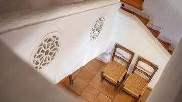 Una escalera con paredes blancas y ornamentados círculos, que conduce a una habitación con dos sillas de madera.