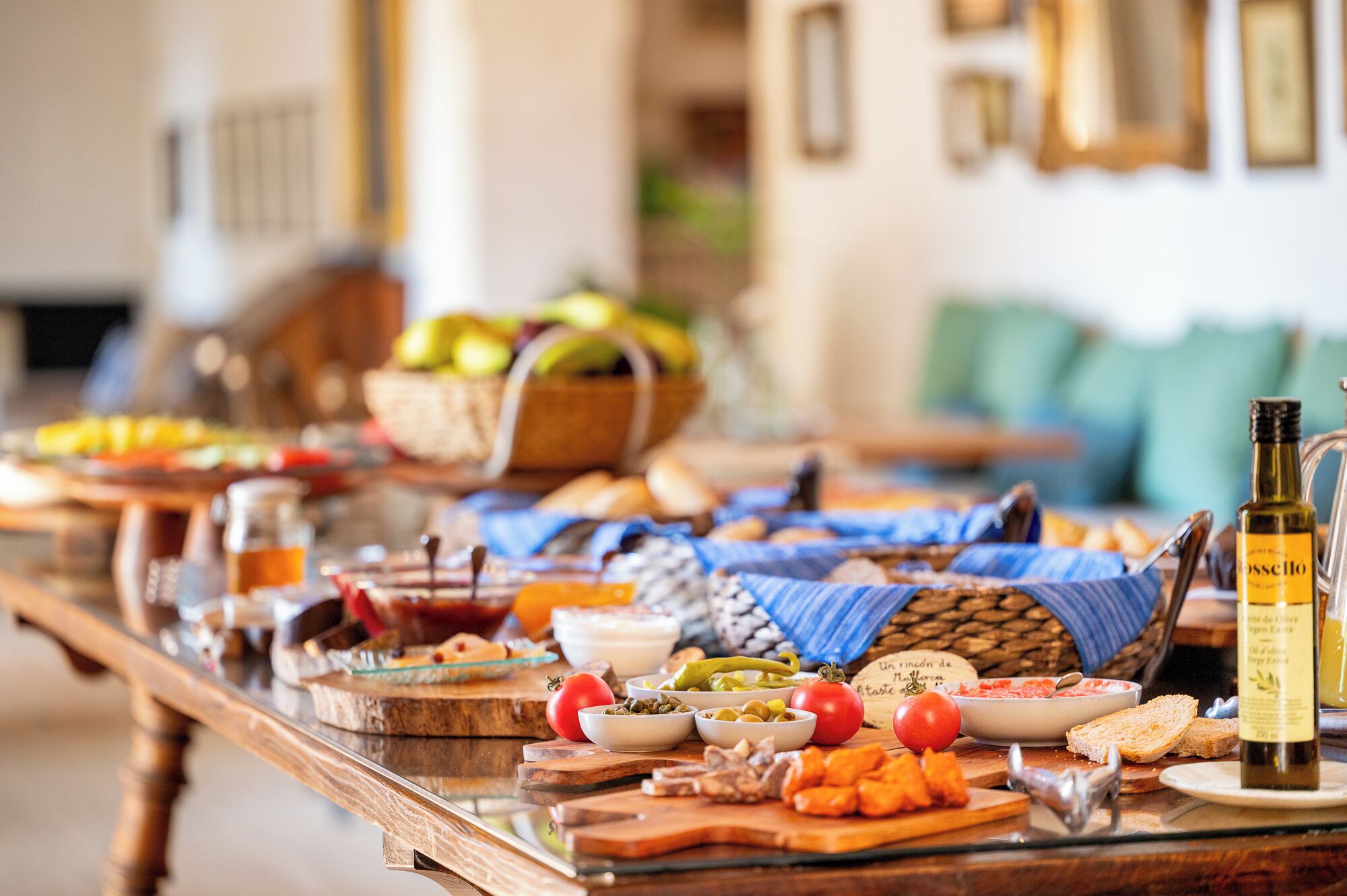 Una mesa de buffet con diversos platos, una botella de aceite de oliva y una cesta de mimbre al fondo.