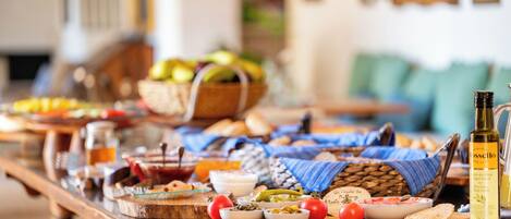 A buffet table with various dishes, a bottle of olive oil, and a wicker basket in the background.