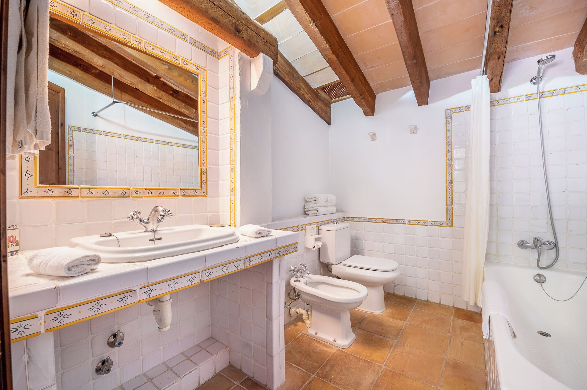 A bathroom with a sink, toilet, bidet, and bathtub.