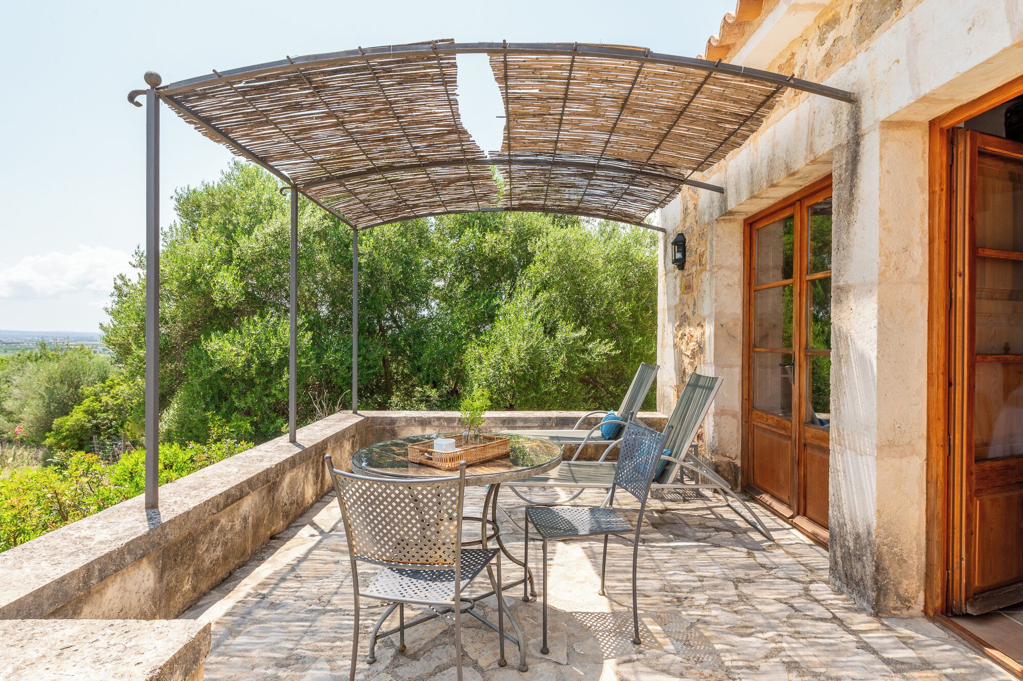 Une terrasse extérieure dotée d’une pergola, d’une table ronde et de deux chaises.