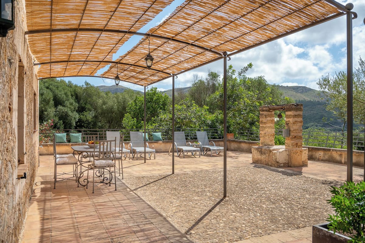 Een terras buiten met een pergola, een zithoek en uitzicht op het omliggende landschap.
