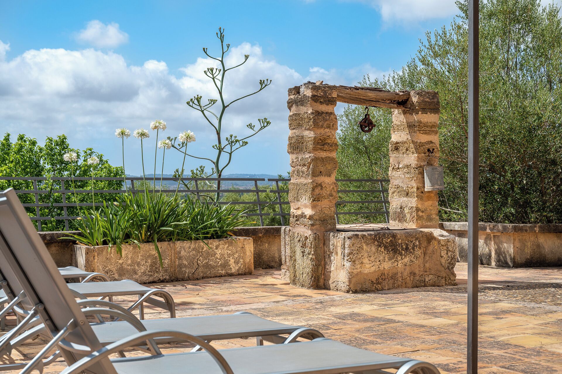 Un arco de piedra, sillas de descanso y vistas al mar.