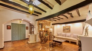 A rustic interior with exposed beams, a stone wall, a wooden bench, and a sofa. - Petit Hotel Restaurante Ses Rotges - Adults Only (Capdepera)