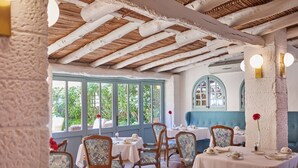 A dining area with wooden beams, tables set for tea service, and large windows with a view of greenery. - Petit Hotel Restaurante Ses Rotges - Adults Only (Capdepera)