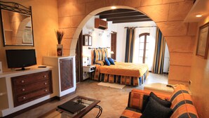 A cozy hotel room with a bed, a sofa, a TV, and a desk. - Petit Hotel Restaurante Ses Rotges - Adults Only (Capdepera)