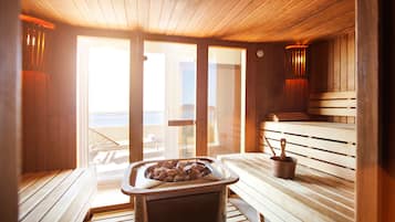 Una sala de sauna con bancos de madera, un calentador para bancos y un cubo.