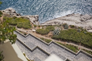 A coastal landscape with rocky terrain, a pebble path, and dense greenery. - Hotel Croatia (Konavle)