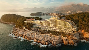 Ein Hotel an der Küste mit mehreren Etagen, gelegen auf einer felsigen Klippe mit Blick aufs Meer.
