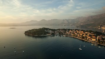 Uma vila costeira com um porto de recreio, edifícios ao longo da orla marítima e montanhas ao fundo.