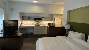 Une chambre d’hôtel équipée d’un lit, d’une télévision, d’une kitchenette et d’un bureau.