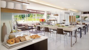 Une cuisine moderne dotée d’un bar pour prendre le petit-déjeuner, de grandes fenêtres et d’une vue sur l’extérieur.