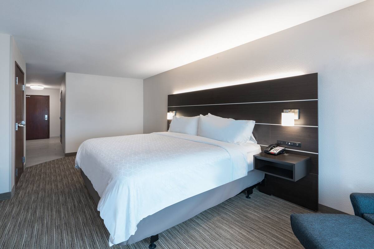 A hotel room with a large bed, bedside tables, a desk, and a chair.