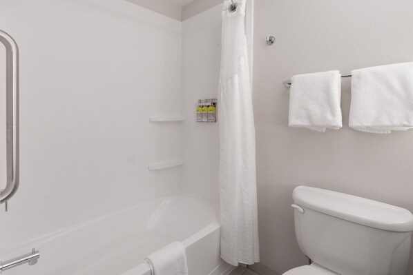 Un baño con bañera, inodoro y cortina de ducha.