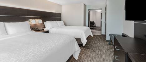 A hotel room with two beds, a desk, a flat-screen TV, and a walk-in closet.