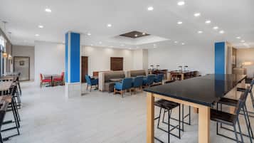 A modern dining area with multiple seating options, including booths and tables, and a central bar area.