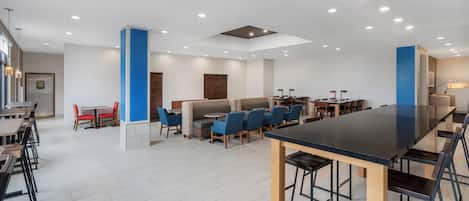 A modern dining area with multiple seating options, including booths and tables, and a central bar area.