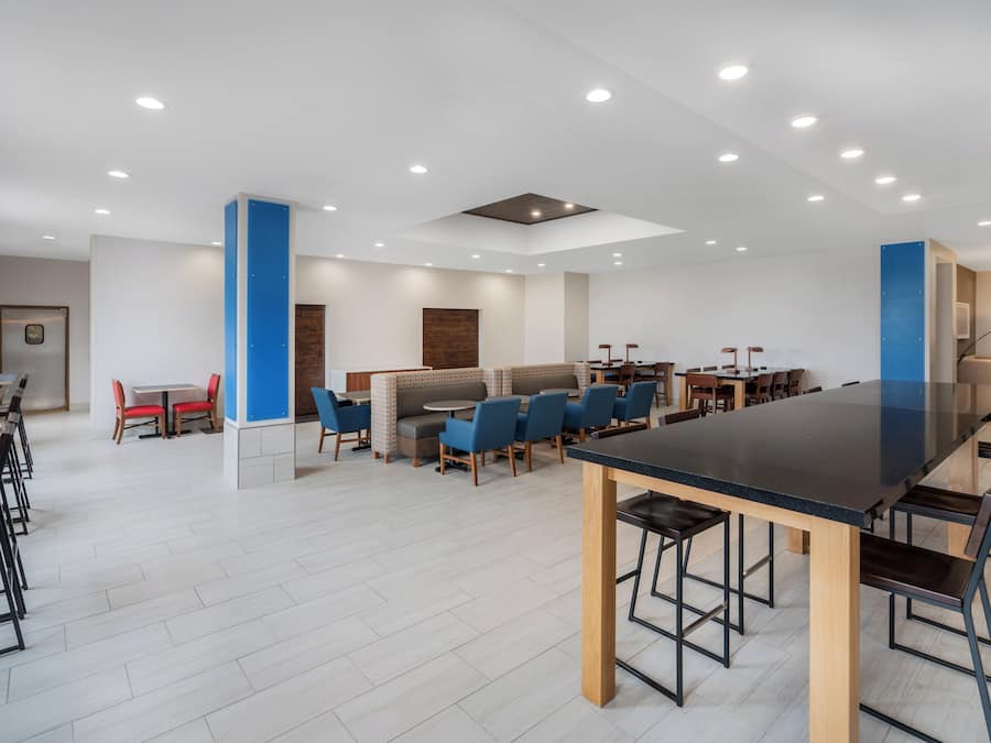 Un comedor moderno con diversas opciones de asientos, incluyendo boxes y mesas, y una zona de bar central.