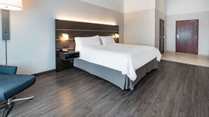 Una habitación de hotel moderna con una cama grande, mesitas de noche, un escritorio y una silla.