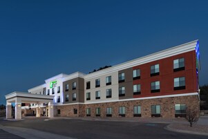 A multi-story hotel with a flat roof, a large entrance with a covered area, and a parking lot in front.