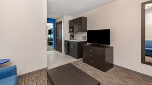 Una sala de estar moderna con televisor de pantalla plana, muebles de madera oscura y un sofá azul.