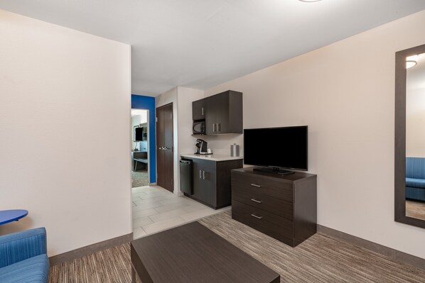 A modern living room with a flat-screen TV, dark wooden furniture, and a blue sofa. - Holiday Inn Express & Suites Trinidad by IHG (Trinidad)