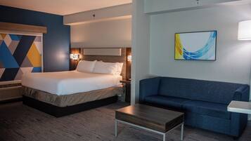 A hotel room with a bed, a sofa, a small table, and a wall-mounted painting.