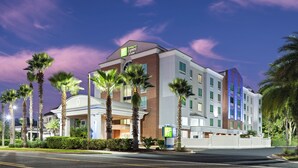 Ein Holiday Inn Express Hotel mit modernem Design, mit einer Ziegel-Fassade, mehreren Stockwerken und einem markanten Eingang mit Palmen.
