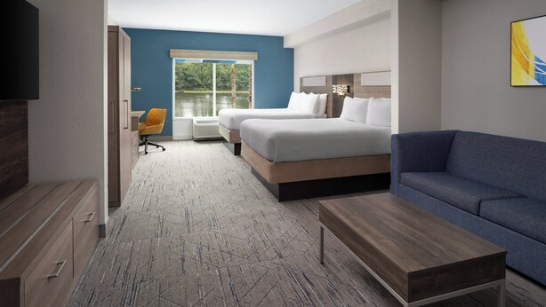 Ein modernes Hotelzimmer mit einem großen Bett, einer Couch, einem Schreibtisch und einem Fernseher.