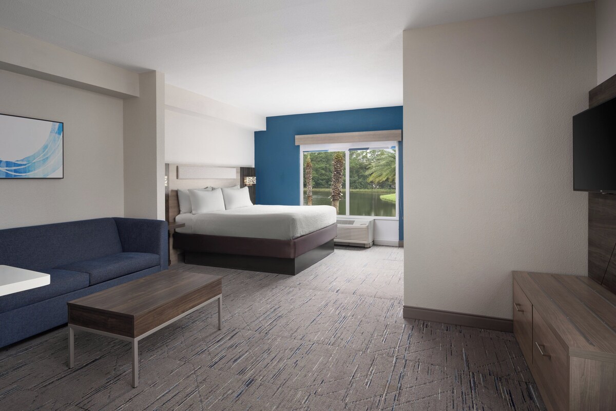 Een moderne hotelkamer met een bed, een blauwe bank, een houten salontafel en een televisie.
