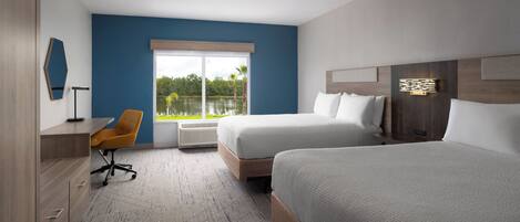 A hotel room with a large bed, a desk, a chair, and a view of a lake.