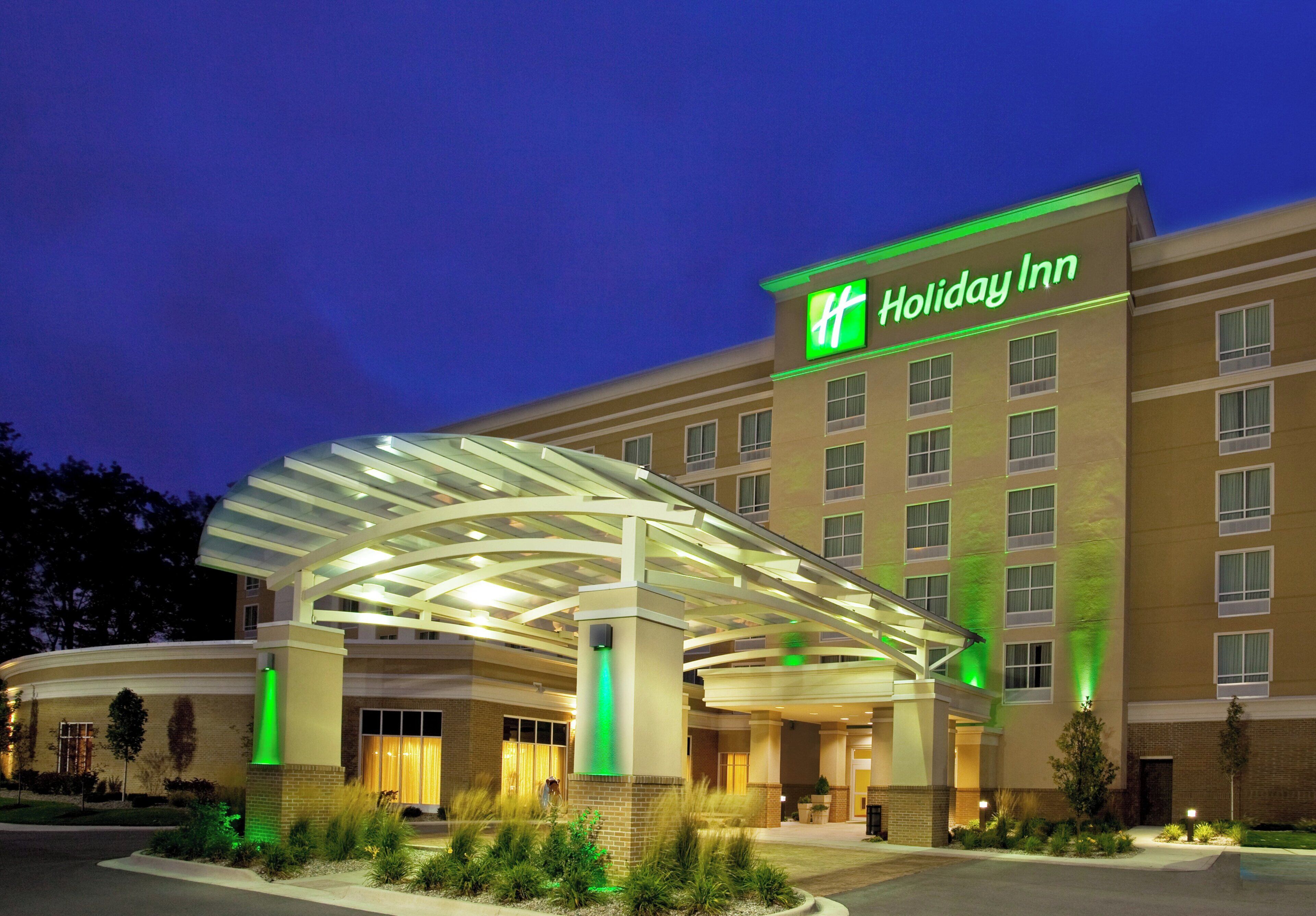 Un hotel Holiday Inn con entrada cubierta y fachada iluminada.