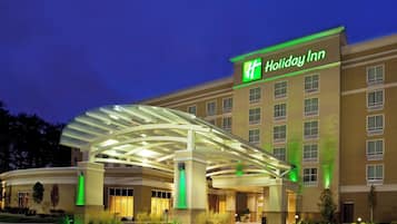 Un hotel Holiday Inn con entrada cubierta y fachada iluminada.