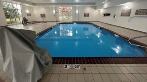 An indoor swimming pool with a covered area, tiled flooring, and safety signs on the walls.