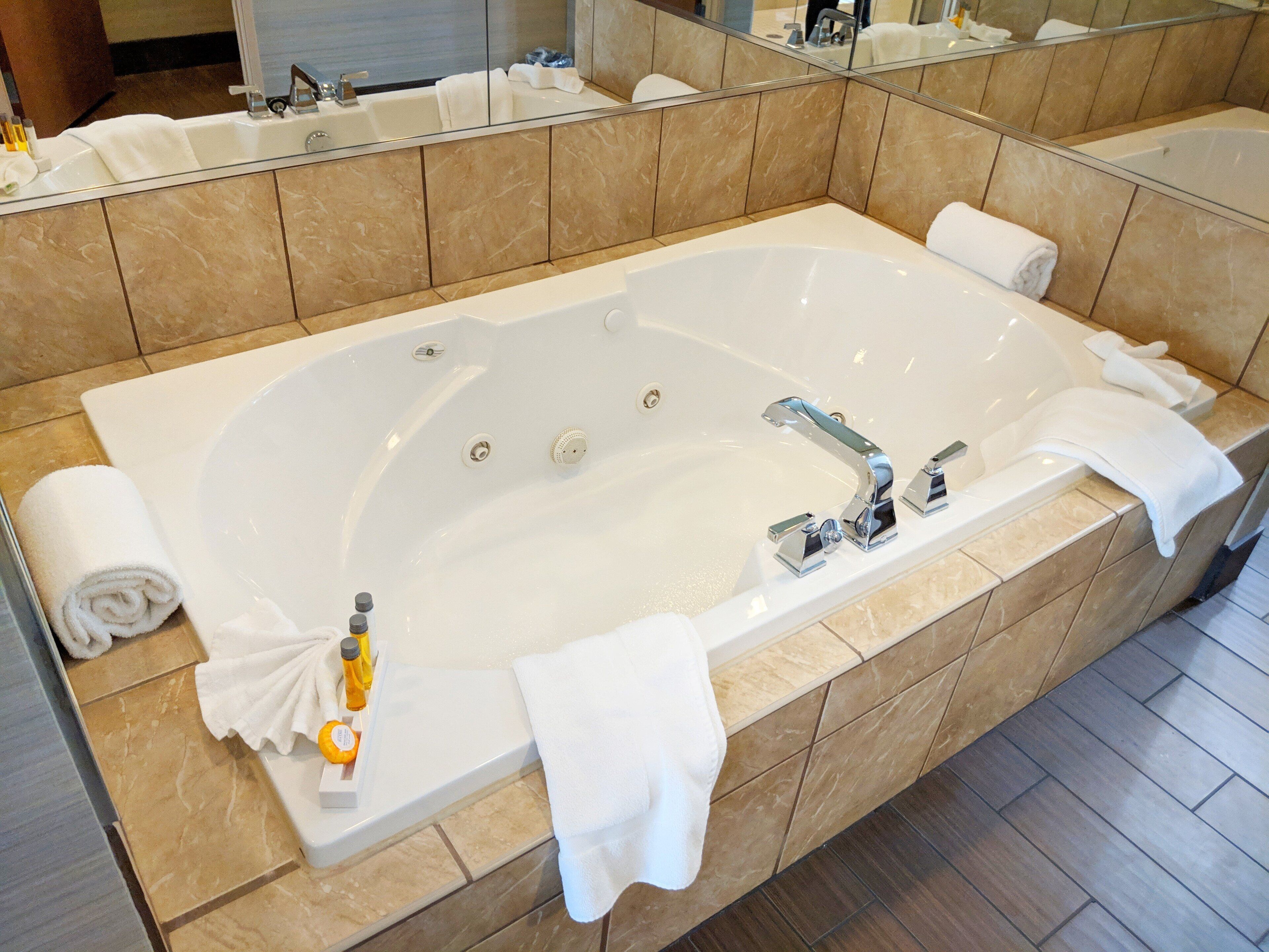 Une salle de bain moderne avec une grande baignoire, un miroir et un porte-serviettes.
