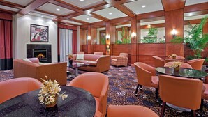 A hotel lobby with a fireplace, seating area, and decorative plants.