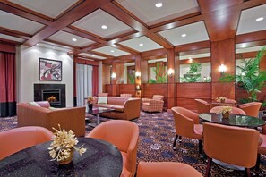 A hotel lobby with a fireplace, seating area, and decorative plants.