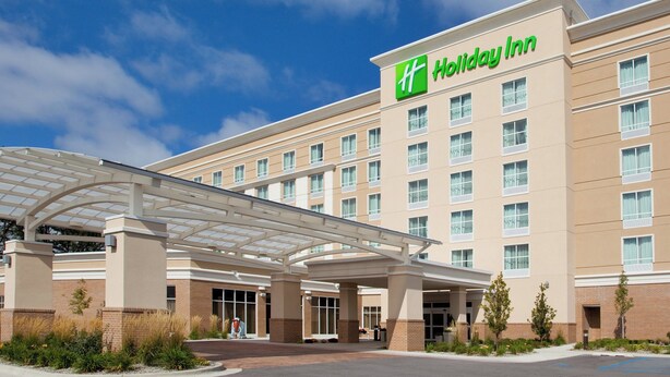 A Holiday Inn hotel with a covered entrance, multiple floors, and a clear sky.