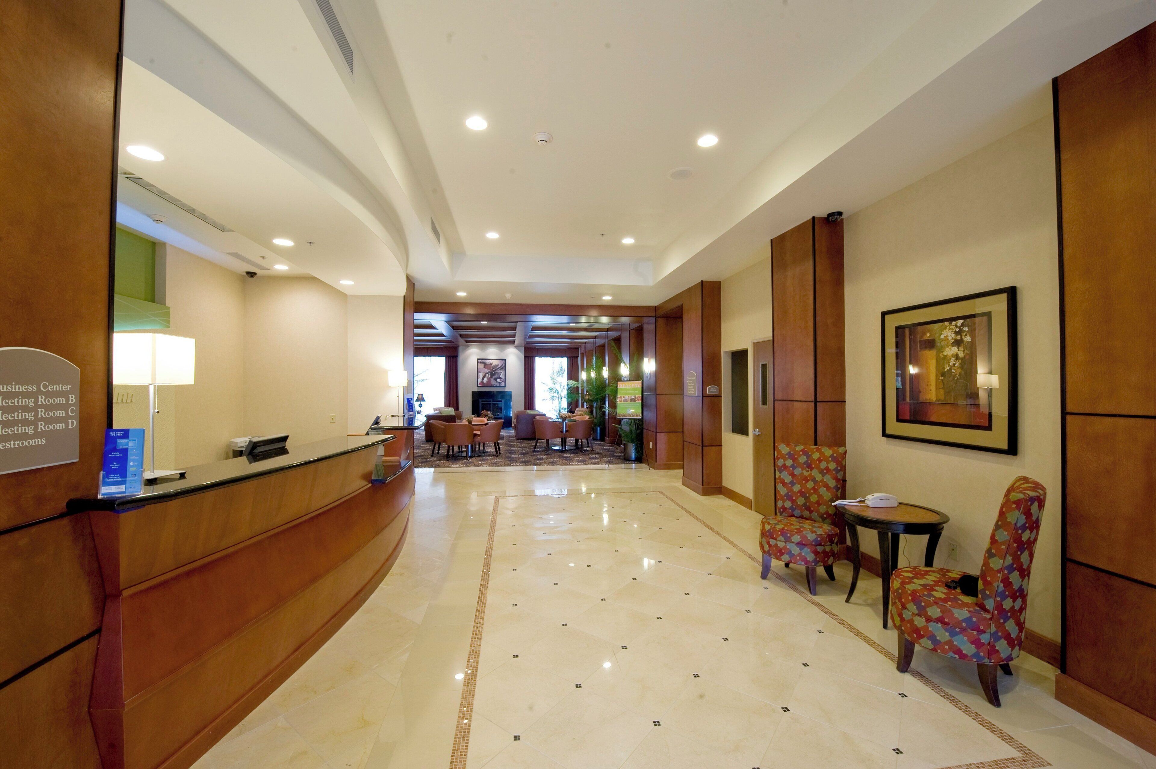 A hotel lobby with a reception desk, seating area, and a hallway leading to meeting rooms.
