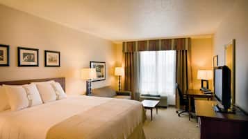 A hotel room with a large bed, two bedside tables, a desk, a chair, and a television.