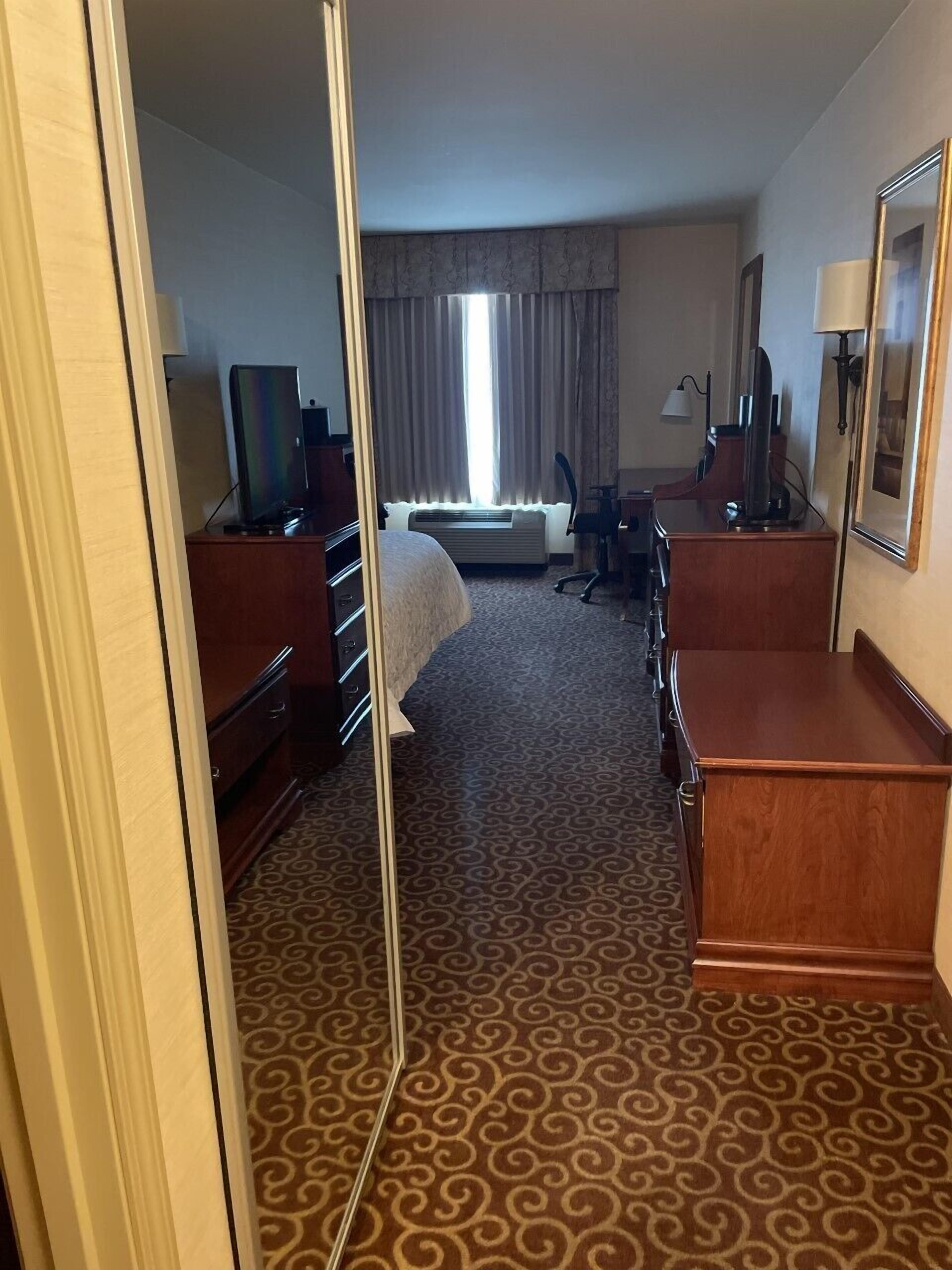 Una habitación de hotel con cama, escritorio, cómoda, silla y televisor.