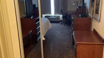 Una habitación de hotel con cama, escritorio, cómoda, silla y televisor.