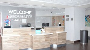 A reception desk with a 'WELCOME TO THE EQUALITY STATE' sign, a coffee machine, and a trash can. - Hampton Inn Rawlins (Rawlins)
